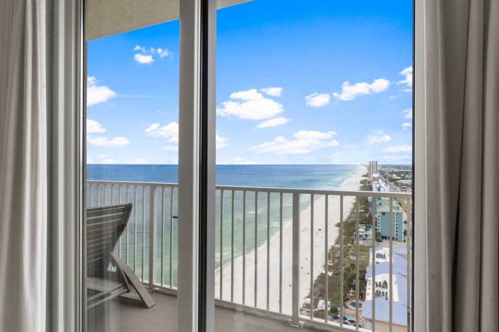 Luxury beachfront condo balcony view looking down at the emerald water and white sand in Panama City Beach