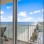 Luxury beachfront condo balcony view looking down at the emerald water and white sand in Panama City Beach