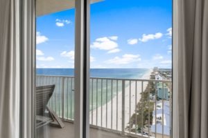 Luxury beachfront condo balcony view looking down at the emerald water and white sand in Panama City Beach