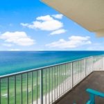 High-rise condo balcony view looking out over a turquoise Gulf ocean with a clear blue sky in Panama City Beach, Florida.