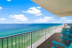 High-rise condo balcony view looking out over a turquoise Gulf ocean with a clear blue sky in Panama City Beach, Florida.