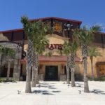 A building and attraction under blue skies surrounded by palm trees.