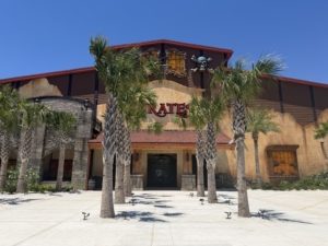 A building and attraction under blue skies surrounded by palm trees.