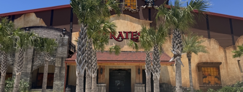 A building and attraction under blue skies surrounded by palm trees.
