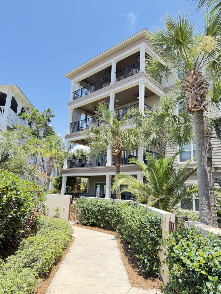 Panama City Beach vacation rental with palm trees and covered balconies managed by Emerald Beach Rentals