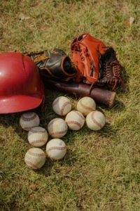 A collection of baseball bats and balls arranged on a turf field.