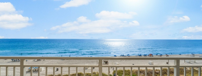 Wide view of white sand, dunes, and blue-green Gulf water from a Panama City Beach condo balcony