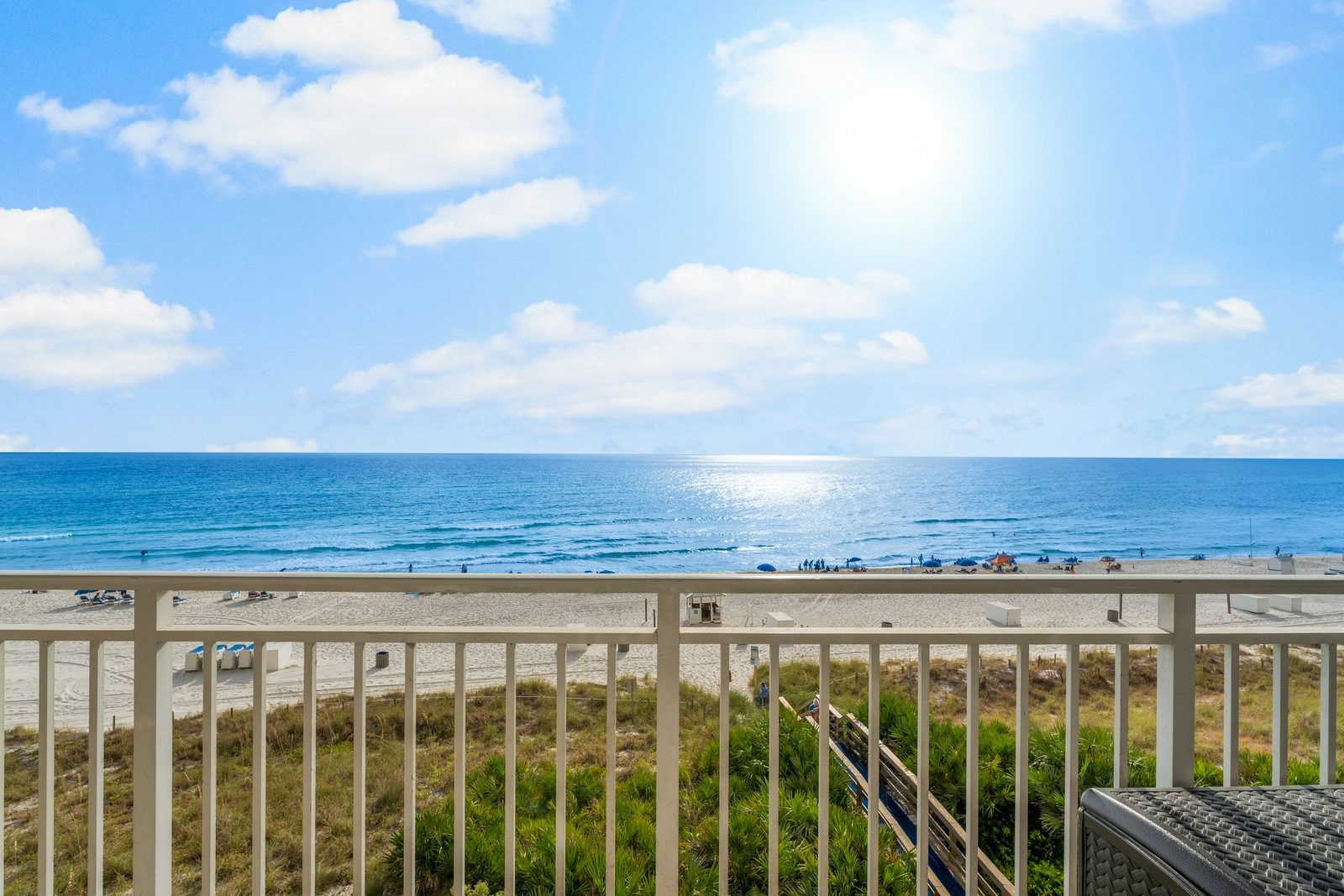 Wide view of white sand, dunes, and blue-green Gulf water from a Panama City Beach condo balcony