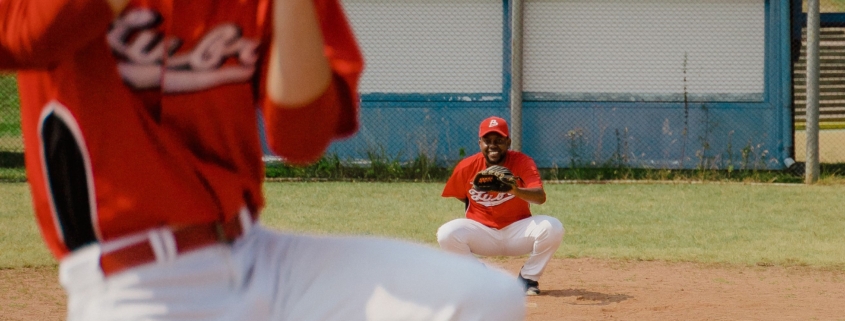 A youth baseball player pitching the ball on a turf field during a tournament.