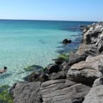 Snorkelers exploring the rock jetties in clear emerald water at St Andrews State Park in Panama City Beach