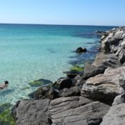 Snorkelers exploring the rock jetties in clear emerald water at St Andrews State Park in Panama City Beach