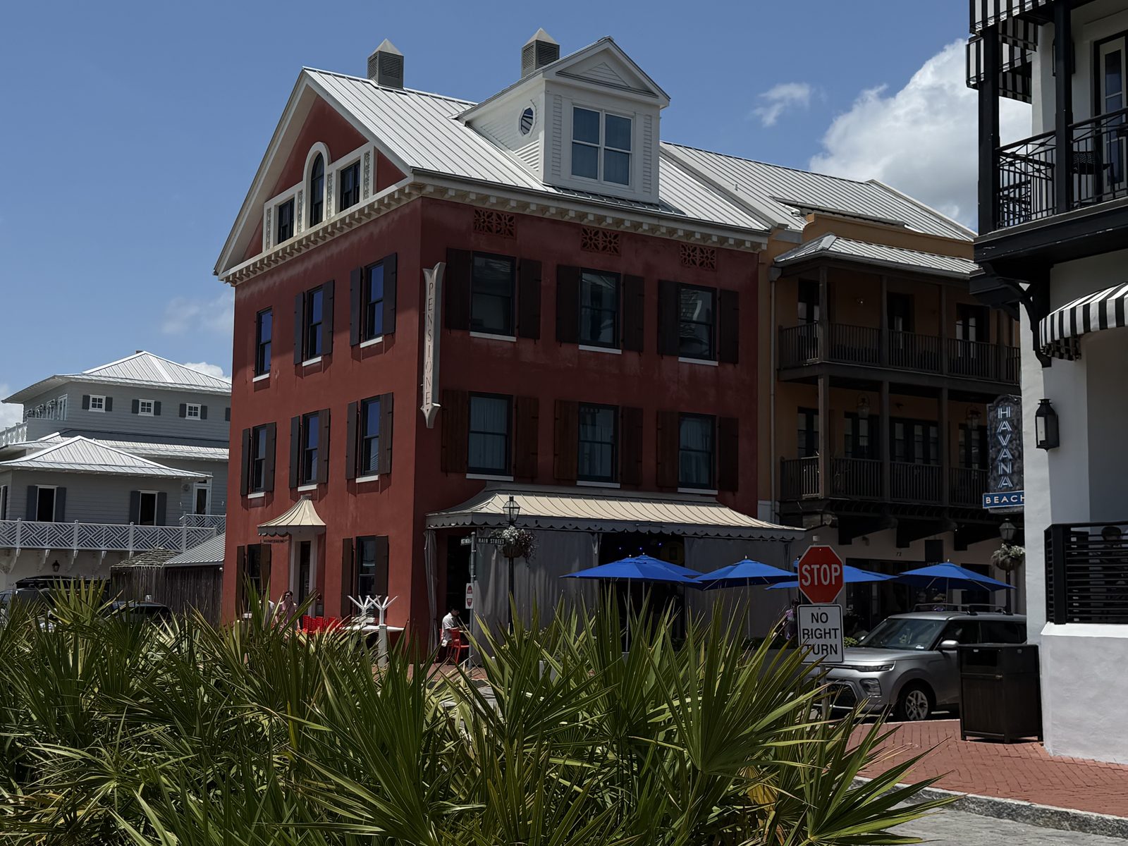 Red brick building with white trim and blue patio umbrellas in the Rosemary Beach town center